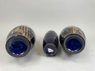 two blue vases with gold designs on them sitting on a white surface