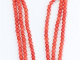 a red beaded necklace with a gold clasp on a white background