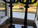 two black candelabs on a table in front of a window