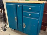 une armoire bleue à deux portes avec un plateau en bois