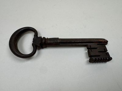 a close up of an old key on a white surface