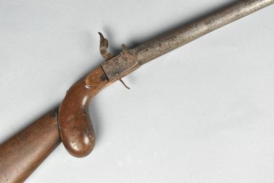 un gros plan d'un fusil à crosse en bois posé sur une surface blanche
