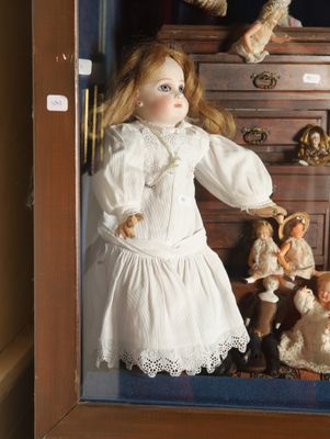 a doll in a display case with many dolls in it