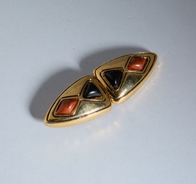 une broche dorée et noire sur un fond blanc