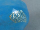 a blue vase with a gold leaf design on it