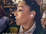a woman with ear buds in her ear wearing a green and yellow shirt