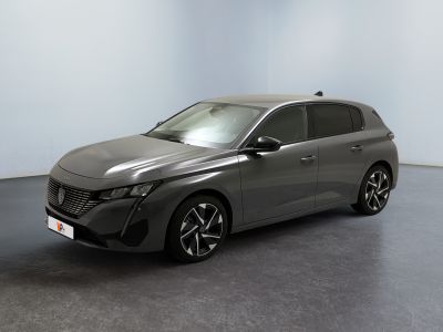 La voiture grise est garée dans une grande pièce au sol noir.