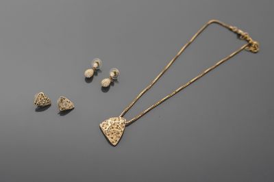 a gold necklace and earring set with a heart shaped pendant