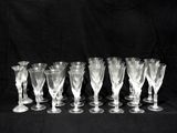 six clear wine glasses are lined up on a black background