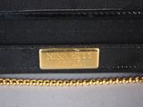 a close up of a black purse with a gold plate on it