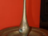 a metal object on a table with a red wall in the background