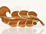 a gold leaf brooch on a white surface