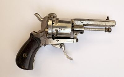 un vieux revolver avec une poignée en bois sur une surface blanche