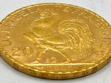 gold coin with a rooster on it on a white surface