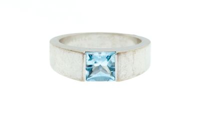 a white gold ring with a blue topaz stone in the center