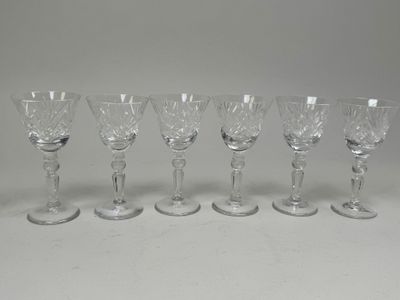six crystal wine glasses lined up in a row on a table