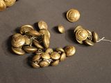 some gold buttons are laying on top of a black surface