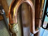 a large copper pipe with a handle next to a wall