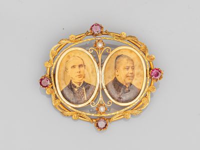un gros plan sur une broche en or représentant deux portraits, celui d'un homme et celui d'une femme