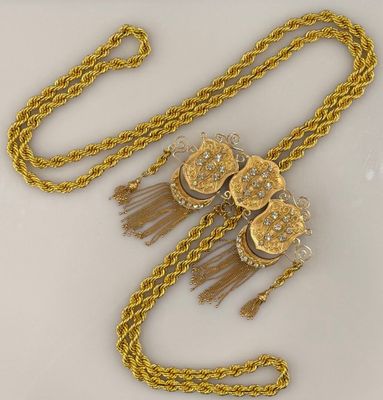 chaîne en or jaune ornée de perles et de pompons sur un fond blanc