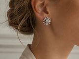 a woman wearing a white shirt and a pair of earrings