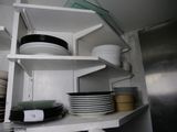 many plates and bowls on the shelves in the kitchen