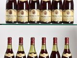 Plusieurs bouteilles de vin sont posées sur une étagère en verre devant un mur blanc.