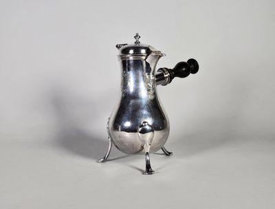 une cafetière ancienne en argent avec une poignée noire sur fond blanc