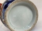 a blue and orange vase sitting on a white surface