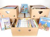 Plusieurs cartons de livres pour enfants sont empilés les uns sur les autres.