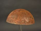 rusty helmet on a metal stand against a black background