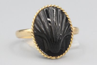 gros plan d'une bague en or contenant une pierre noire