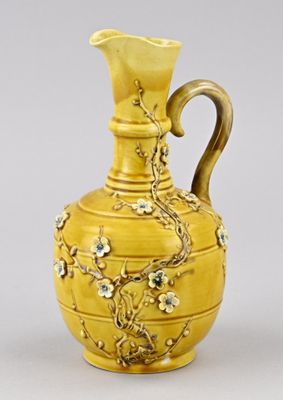 un vase jaune orné de fleurs, posé sur une table