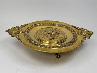 a gold plate with an ornate design on it on a white surface