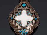 a close up of a silver broochle with a cross on it