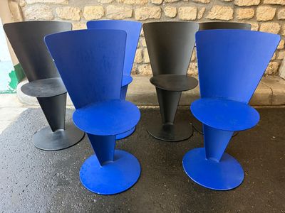 trois chaises bleues et noires placées les unes à côté des autres devant un mur de pierre