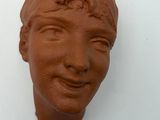 a clay sculpture of a woman ' s face on the wall