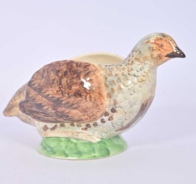 a ceramic bird on a green base on a white background