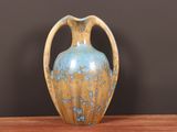 a blue and yellow vase sitting on a wooden table