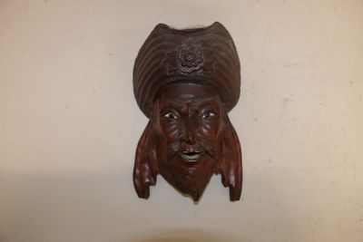 une sculpture en bois représentant un homme coiffé d'un chapeau