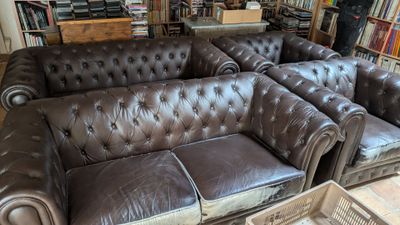 un canapé en cuir marron placé devant une bibliothèque