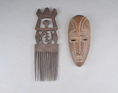 two wooden combs and a wooden mask on a table