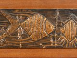 a wooden plaque with a fish design on it