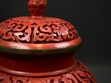 a red vase with a lid sitting on a table