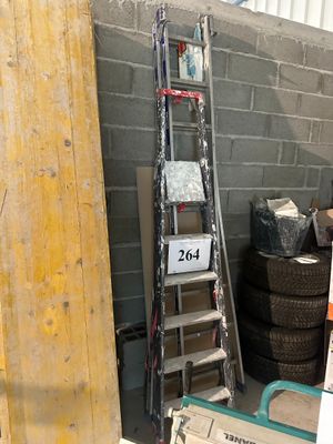 une échelle appuyée contre un mur, à côté d'un tas de pneus