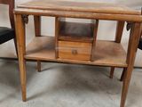 a small table with a drawer on it next to a chair