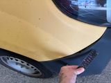 a man holding a remote control in front of a yellow car