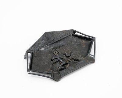 un objet métallique sur lequel est représenté un oiseau, posé sur une surface blanche