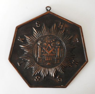 une plaque métallique sur laquelle figurent un soleil rayonnant et une horloge