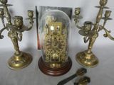 three brass candlesticks and a glass dome with a clock in it